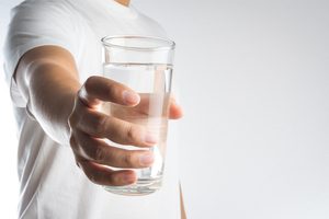 mužská ruka podávajúca pohár s vodou