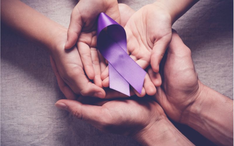tri páry rúk spoločne držiace fialovú stužku - rakovina pankreasu