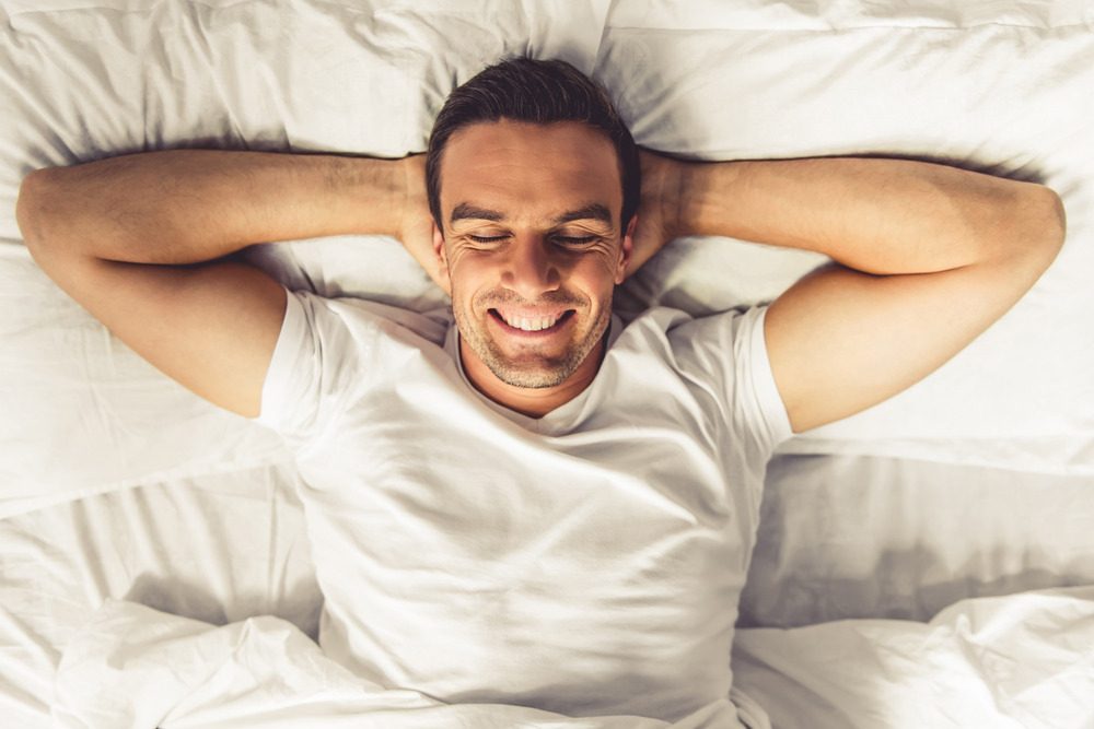 šťastný muž leží na posteli